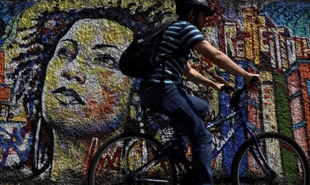 FILE PHOTO: A man rides past a graffiti in tribute of late councilwoman Marielle Franco, murdered last year in Rio de Janeiro