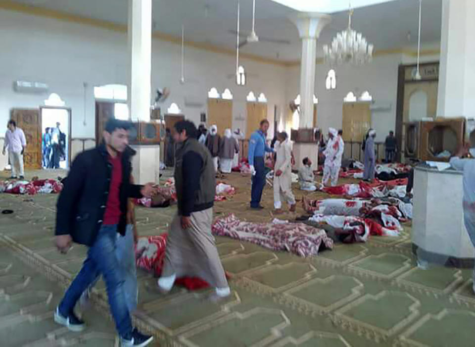 <p>Egyptians walk past bodies following a gun and bombing attack at the Rawda mosque, roughly 40 kilometers west of the North Sinai capital of El-Arish, on Nov. 24, 2017. (Photo: Stringer/AFP/Getty Images) </p>