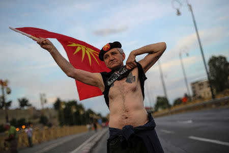 A supporter of opposition party VMRO-DPMNE waves a flag and shows his tattoo as he takes part in a protest over compromise solution in Macedonia's dispute with Greece over the country's name, in Skopje, Macedonia, June 2, 2018. REUTERS/Marko Djurica