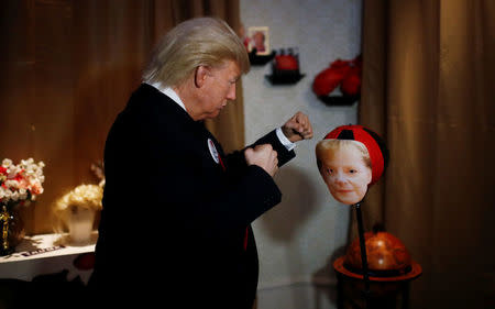 A performer with a mask of U.S. President Donald Trump hits a punching ball with a mask of German Chancellor Angela Merkel in the Madame Tussauds wax museum in Berlin, Germany, August 14, 2018. REUTERS/Hannibal Hanschke