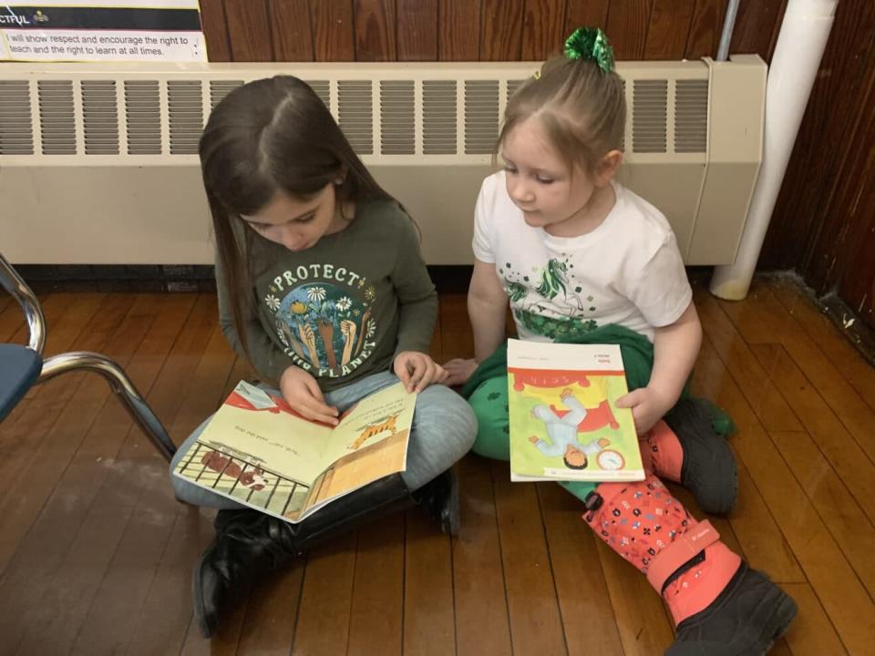 First grader Sophia Grassie (left) and Kindergarten student Leah Tobey (right) read books to honor Dr. Seuss' birthday.