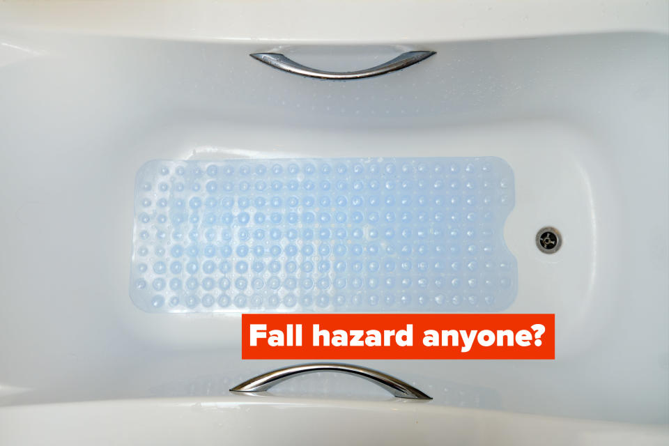 A clear silicone bathtub mat is pictured from above a porcelain bathtub with tub handles on either side