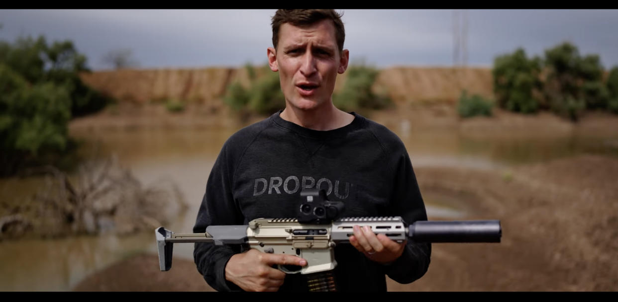 Blake Masters holds a weapon in a November 2021 video campaign ad. 