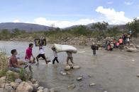 <p>Niños, ancianos y mujeres embarazadas o con bebés en brazos atraviesan el río bajo la aparentemente descuidada mirada de la Guardia Nacional Bolivariana (GNB) de Venezuela que parece haber abierto la mano ante este drama humanitario. Según pudo comprobar Efe, el cruce permanece hoy alejado de la mirada de esos agentes que miran hacia otro lado ante la presencia de centenares de colombianos que sacan sus pertenencias. REUTERS/Juan Pablo Cohen-La Opinion/Handout via Reuters</p>