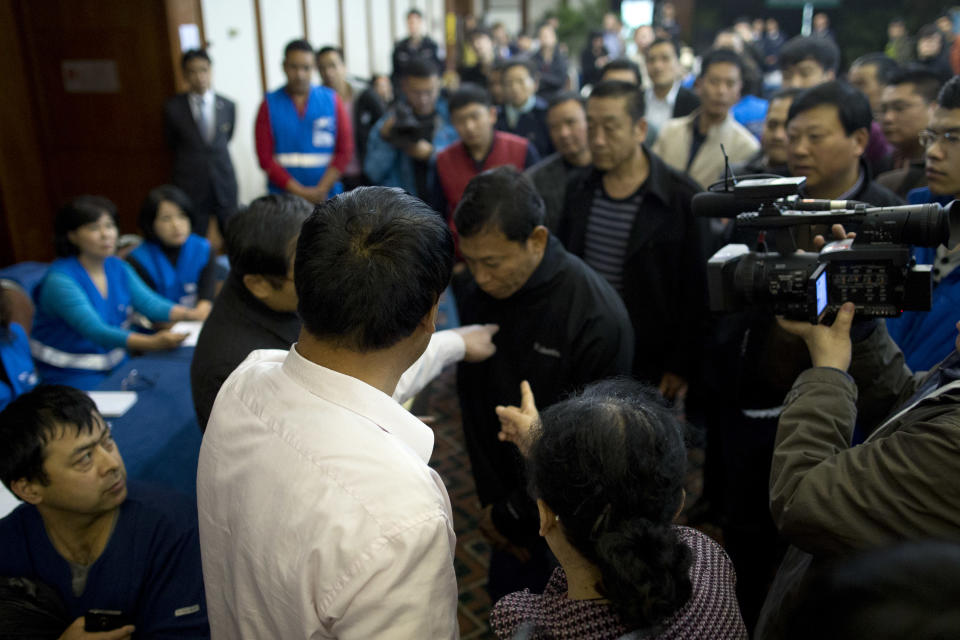 Relatives of Chinese passengers aboard missing Malaysia Airlines Flight MH370, front, blame an employee of Malaysia Airlines after one of their family member was asked for identity credential during a daily briefing meeting with managers of Malaysia Airlines at a hotel ballroom in Beijing, China, Wednesday, March 19, 2014. Search crews from 26 countries are looking for Malaysia Airlines Flight 370, which vanished early March 8 with 239 people aboard en route from Kuala Lumpur to Beijing. Frustration is growing among relatives of those on the plane at the lack of progress in the search. (AP Photo/Alexander F. Yuan)