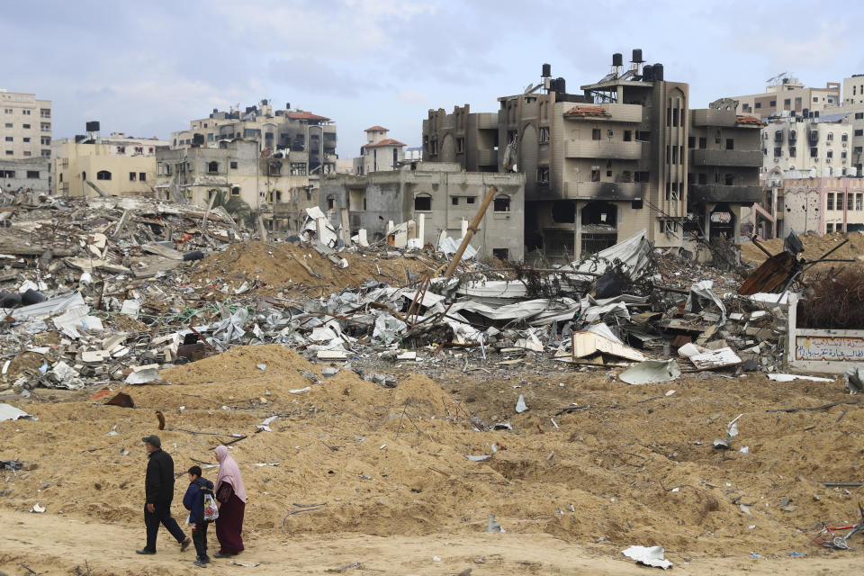 Palestinians walk past the building destroyed in the Israeli Bombardment of the Gaza Strip in Gaza City on Wednesday, Jan. 3, 2024. (AP Photo/Mohammed Hajjar)