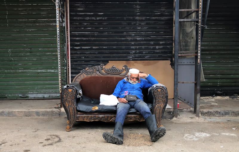 A man sleeps on a couch in front of closed shops in Sabra