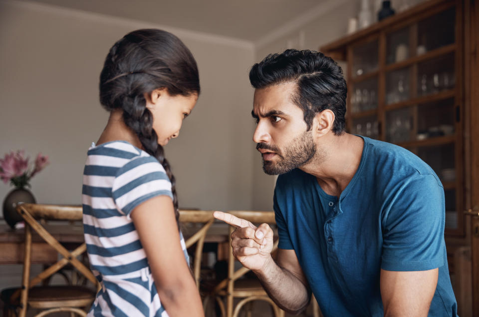 Adult scolding a child, both appear frustrated. The setting is indoors, possibly a dining area