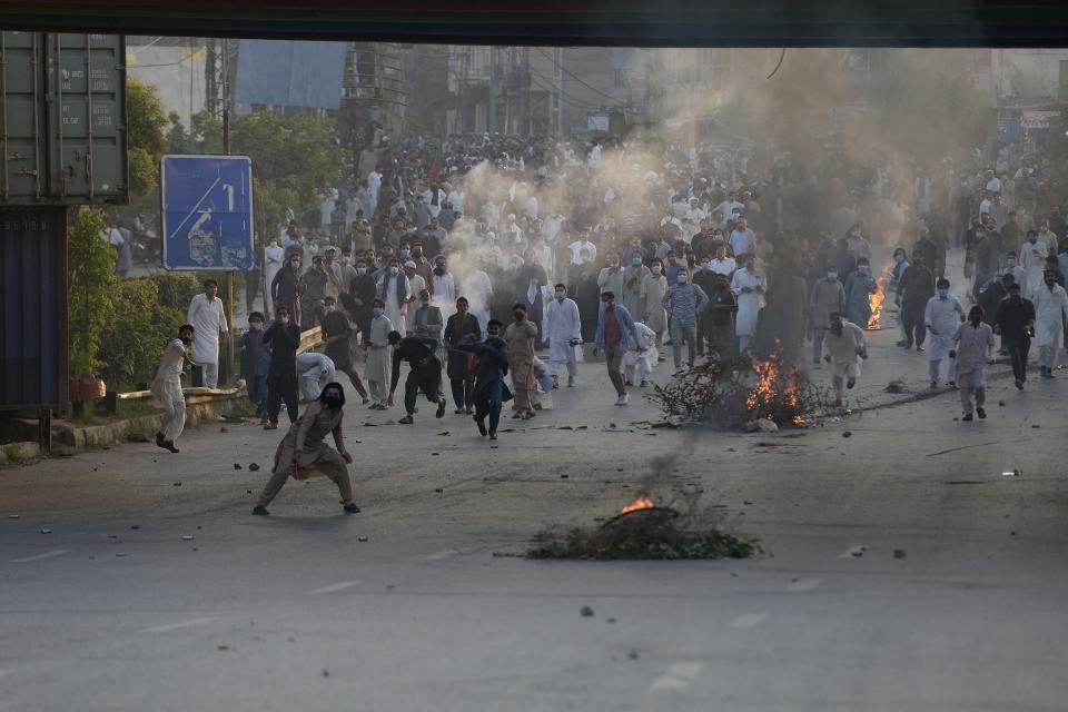 Supporters of former Prime Minister Imran Khan's party throw stones toward police officers during a protest to condemn the election commission's decision, in Islamabad, Pakistan, Friday, Oct. 21, 2022. Pakistan’s elections commission on Friday disqualified former Prime Minister Imran Khan from holding public office for five years, after finding he had unlawfully sold state gifts and concealed assets as premier, officials said. (AP Photo)