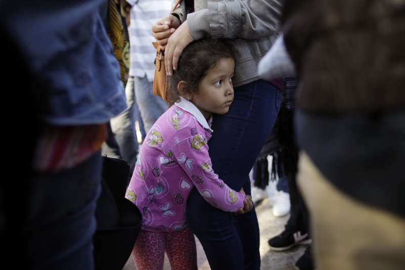 小女孩妮可緊抱著母親大腿，她們來自墨西哥南部格雷羅州，為了逃離家鄉的黑幫暴力，於是來到美墨邊境等待，希望能獲得美國的政治庇護（美聯社）