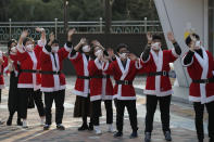 Volunteers wearing face masks wave after they load boxes onto a delivery truck during an event to send Christmas gifts for the underprivileged in Seoul, South Korea, Tuesday, Dec. 22, 2020. The Korea Youth Foundation sent Christmas gifts using a courier to help prevent against the coronavirus as the social distancing measures. (AP Photo/Lee Jin-man)