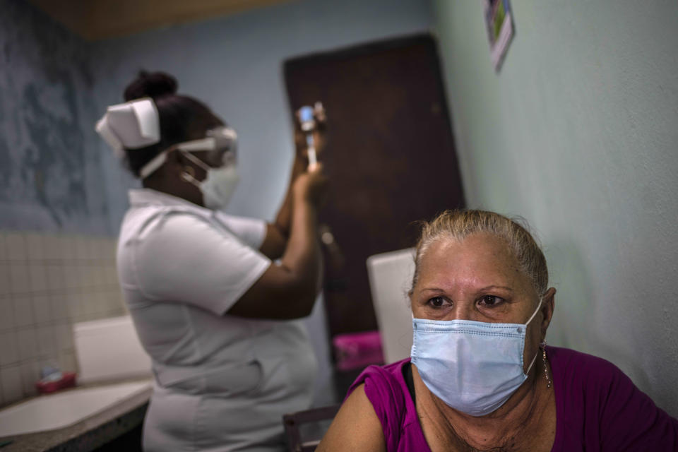 A woman waits to be vaccinated as a nurse prepares the dose of the Cuban Abdala vaccine for COVID-19 at a doctors' office in Alamar on the outskirts of Havana, Cuba, Friday, May 14, 2021. Cuba has begun to immunize people this week with its own vaccines, Abdala and Soberana 02, the only ones developed by a Latin American country. (AP Photo/Ramon Espinosa)