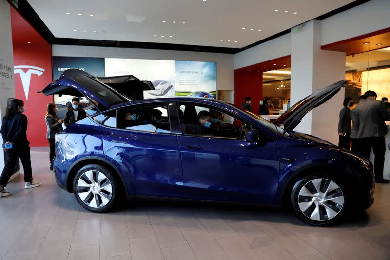 FILE PHOTO: FILE PHOTO: Visitors wearing face masks check a China-made Tesla Model Y sport utility vehicle (SUV) at the electric vehicle maker's showroom in Beijing