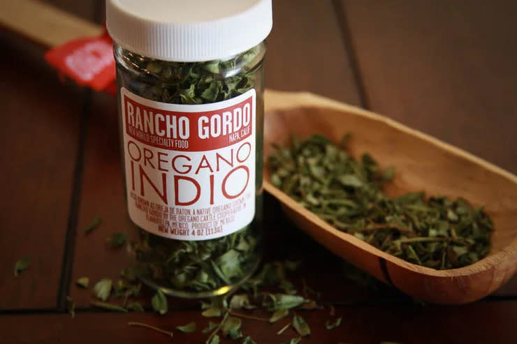 Oregano leaves both in a jar and in a nice wooden bowl. 