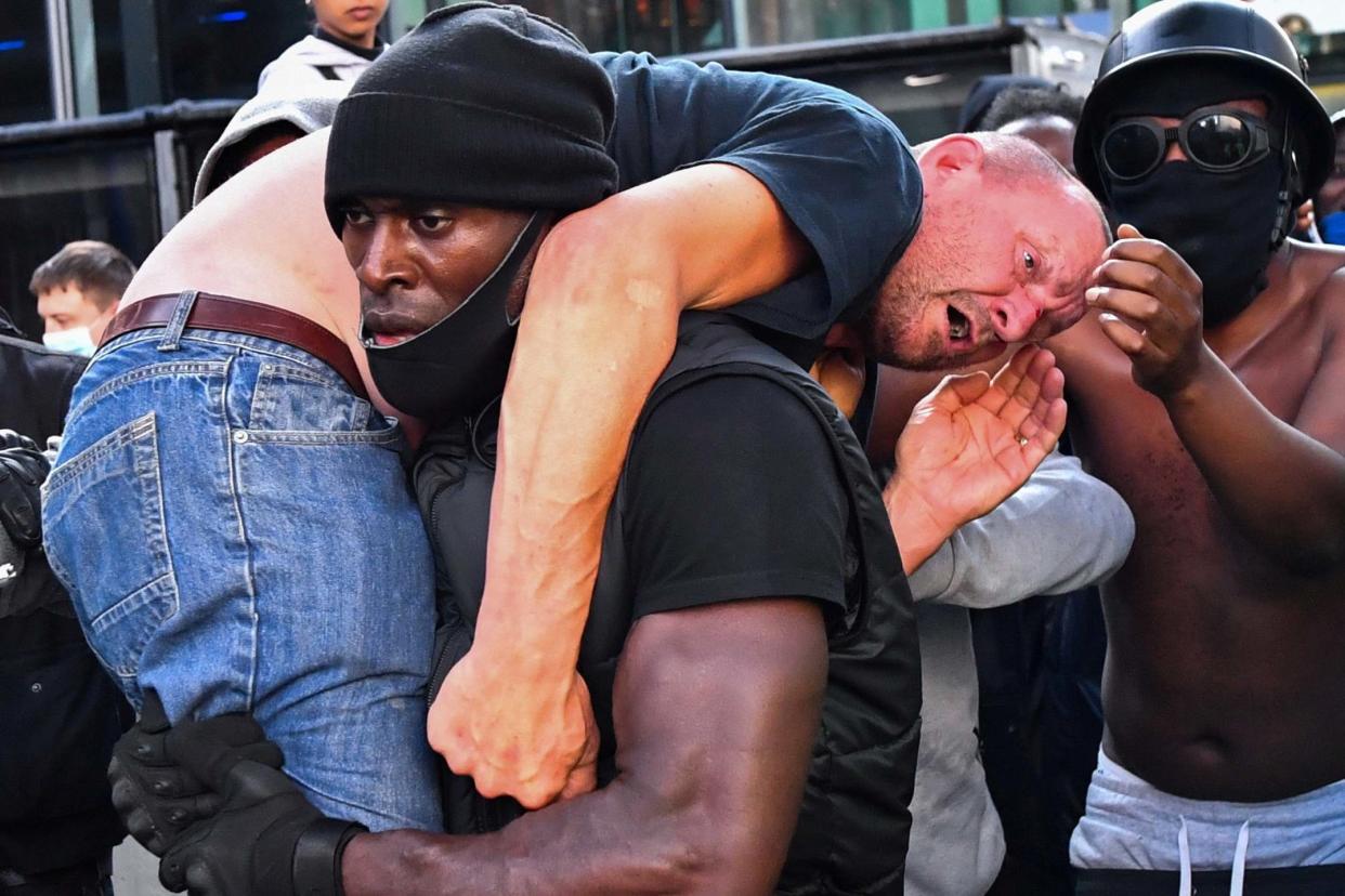 A Black Lives Matter supporter carries an injured counter-protester to safety, near Waterloo station, London: REUTERS