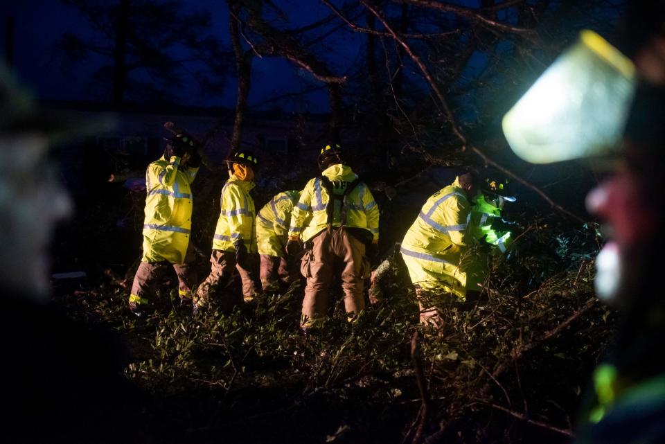 Firefighters cut through trees on the road