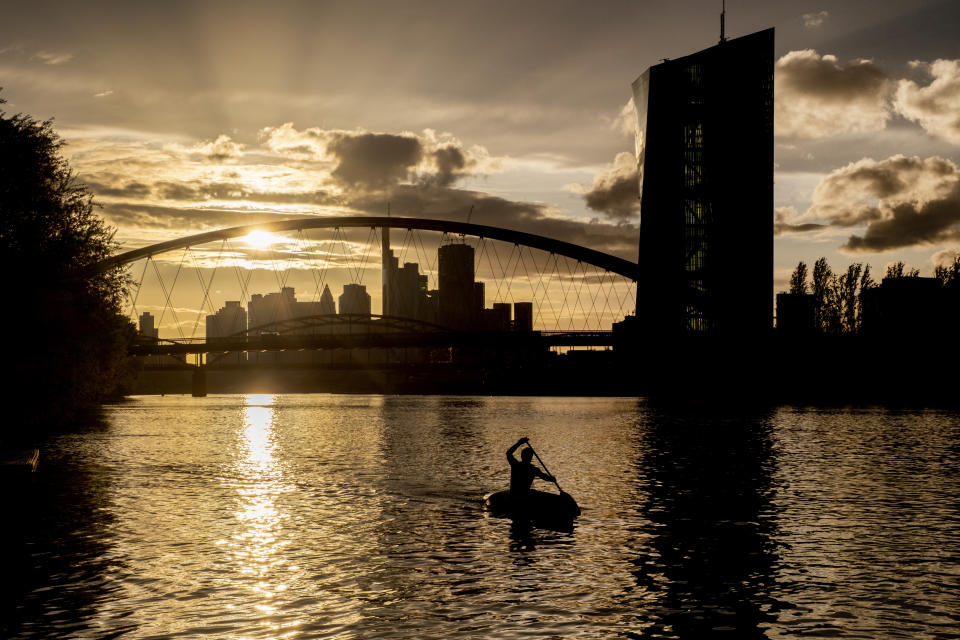 FILE - A man rows along the Main river, with the European Central Bank, right in background, in Frankfurt, Germany, Tuesday, April 9, 2024. Markets are waiting to hear what European Central Bank President Christine Lagarde has to say about the timing of a first interest rate cut. Analysts say the bank isn't likely to change rates at its policy meeting Thursday. (AP Photo/Michael Probst, File)