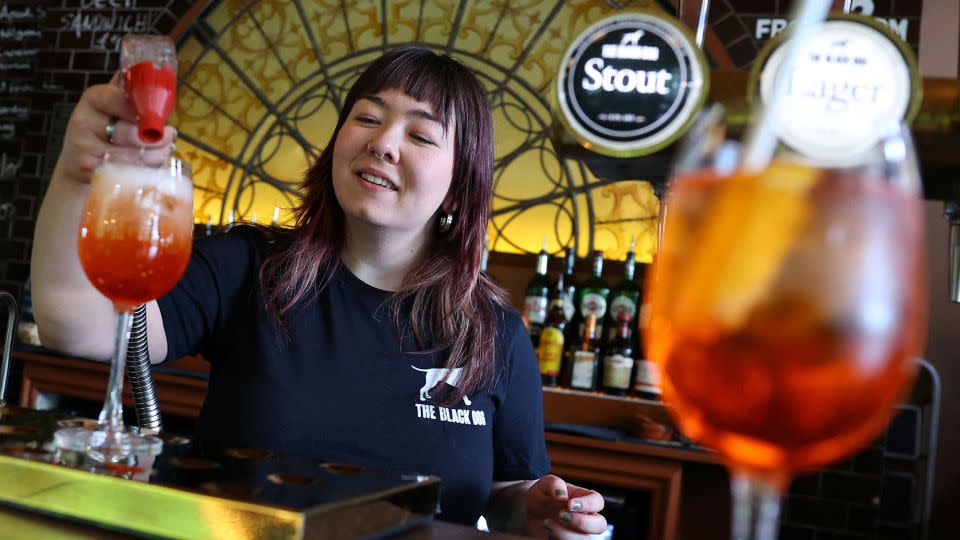 An employee at The Black Dog pub is pictured making an  'Aperol Spritz (Taylor's Version)' cocktail. - Toby Melville/Reuters