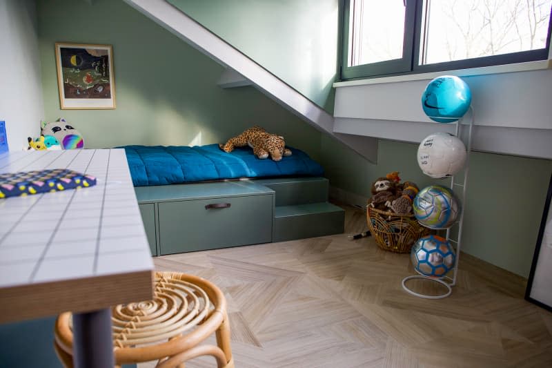 Sports balls stacked in child's bedroom with green wall.