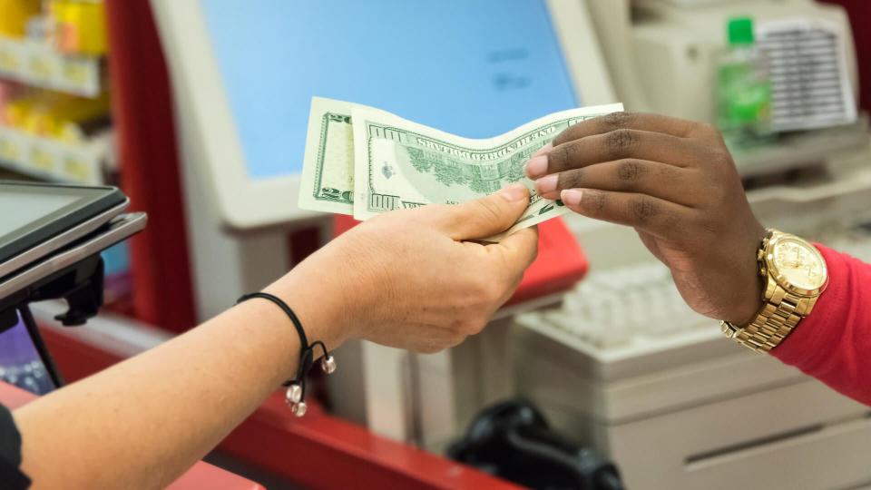 Woman giving cash when paying at a supermarket.