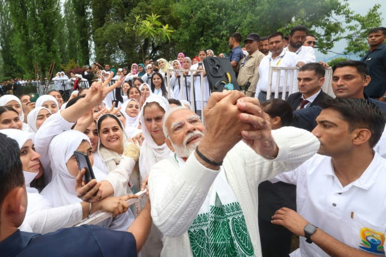 India's Prime Minister Narendra Modi is set to lead his government in its third term in parliament on Monday; here he takes photographs with people on International Day of Yoga in Srinagar on June 21 (-)