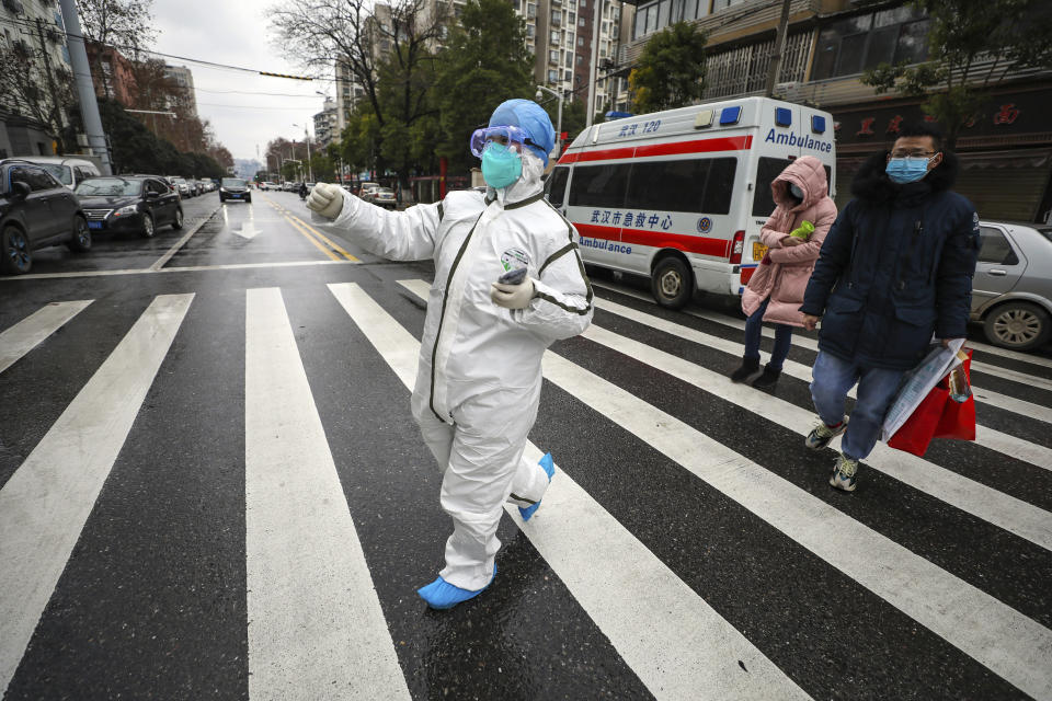 En esta imagen del domingo 26 de enero de 2020, un trabajador médico con traje protector guia a pacientes hacia un hospital en Wuhan, en la provincia de Hubei, en el centro de China. (Chinatopix via AP)