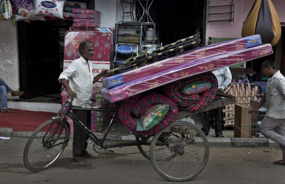 In this Dec. 17, 2018, photo, a cycle rickshaw puller prepares to transport mattresses from the Nampally furniture market in Hyderabad, India. Just 20 kilometers (12 miles) from Hyderabad’s Ikea, Nampally remains a beehive of activity, demand for India’s traditional custom-built furniture remains high. But Ikea already is adding to pressure on Indian furniture sellers’ profits and could eventually take a bigger bite of the market. (AP Photo/Mahesh Kumar A.)