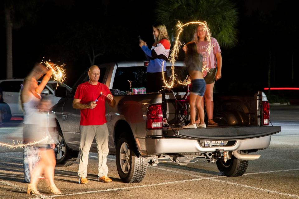 Tim Cable, (center) lights sparklers for family and friends while waiting for fireworks display in Wellington, July 4, 2020
