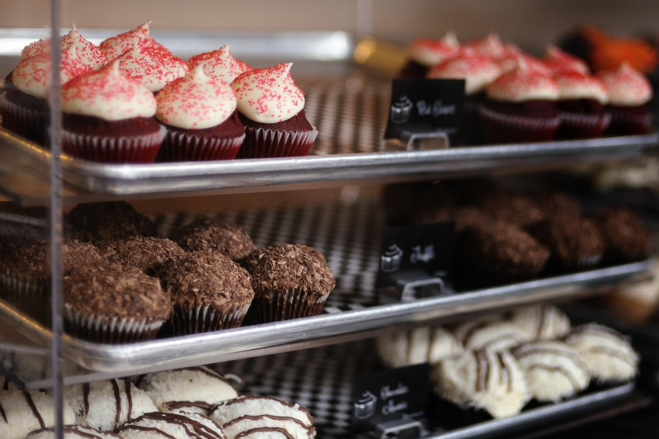 Glass bakery display case with assortment of cupcakes.