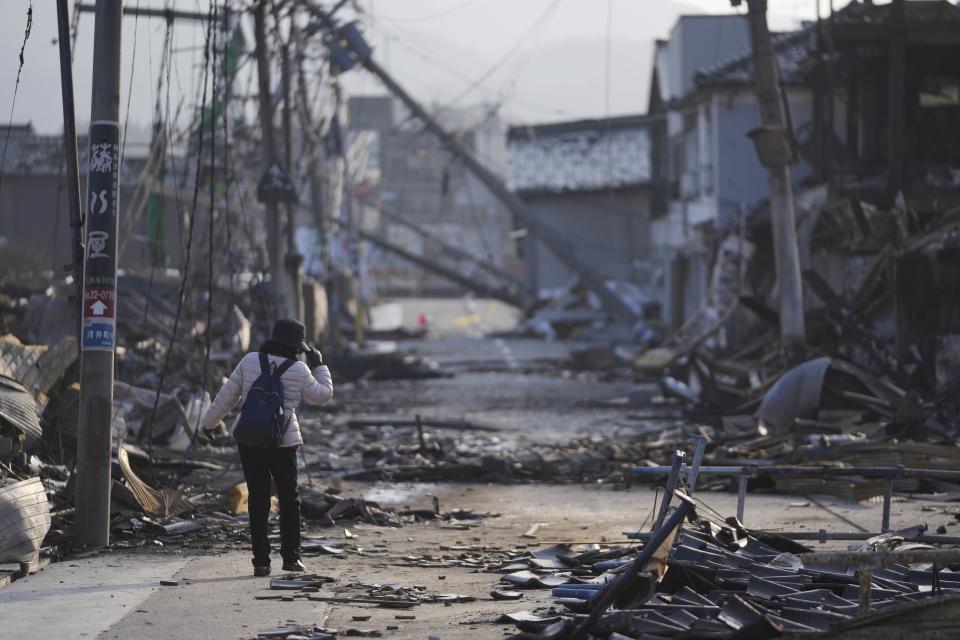 A person walks through a street with debris of damaged and burnt buildings in Wajima in the Noto peninsula, facing the Sea of Japan, northwest of Tokyo, Saturday, Jan. 6, 2024, following Monday's deadly earthquake. (AP Photo/Hiro Komae)