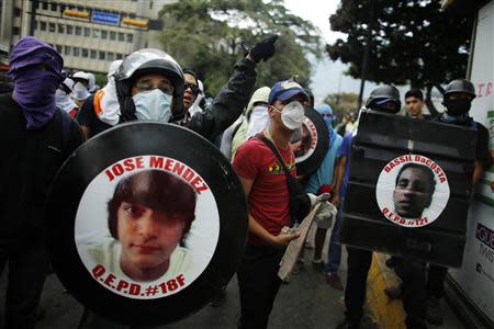 Anti-government protesters hold photographs of victims of violence during a protest at Altamira square in Caracas March 13, 2014. REUTERS/Tomas Bravo