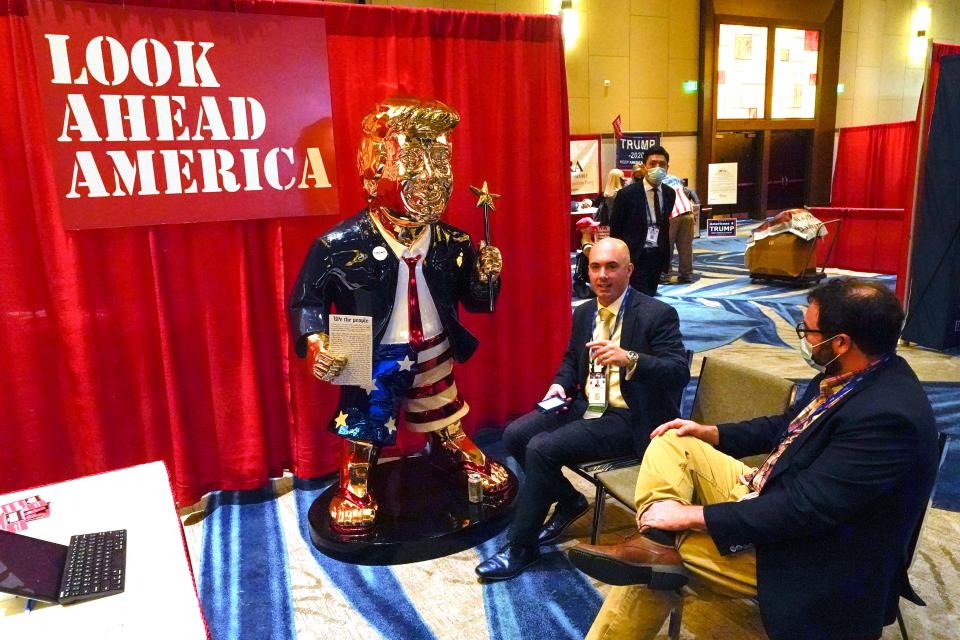 Look Ahead America sponsor Matt Braynard, center, talks to conference attendees at his booth in the merchandise show with a statue of former president Donald Trump at the Conservative Political Action Conference (CPAC) in Orlando, Florida.