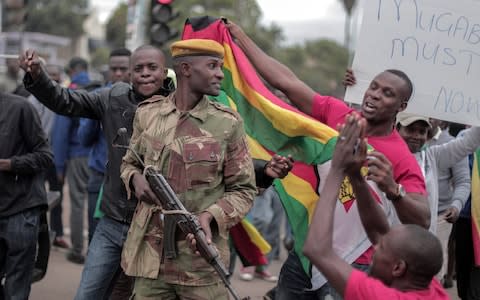 People cheer soldiers during a march in the streets to demand that President Robert Mugabe resign and step down from power in Harare, Zimbabwe, on November 19, 2017 - Credit: Barcroft Media