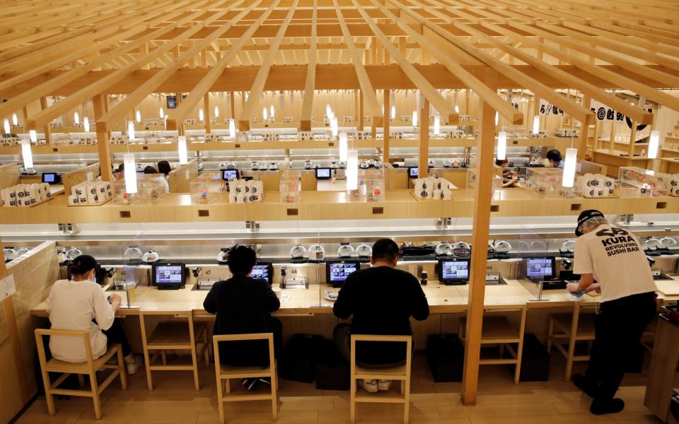 Customers eat sushi off a conveyor belt at a Kura Sushi restaurant in Tokyo, Japan, - Reuters