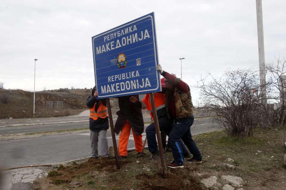 Workers remove a road sign that reads ''Republic of Macedonia'' in the southern border with Greece, near Gevgelija, Wednesday, Feb. 13, 2019. The small Balkan country of Macedonia officially changed its name Tuesday by adding a geographic designation that ends a decades-old dispute with neighboring Greece and secures its entry into NATO. (AP Photo/Boris Grdanoski)