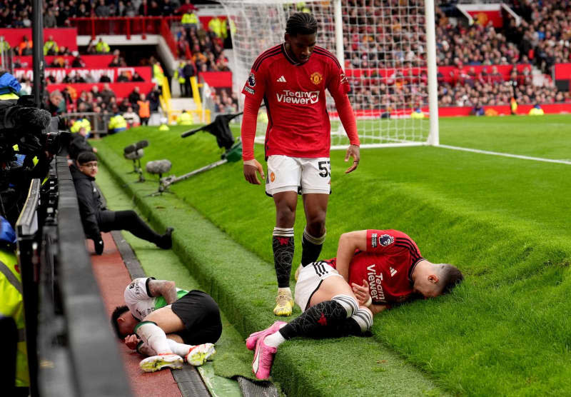 Liverpool FC's Luis Diaz (L) and Manchester United's Diogo Dalot lie on the ground after a collision during  the English Premier League soccer match between Manchester United and Liverpool at Old Trafford. Martin Rickett/PA Wire/dpa