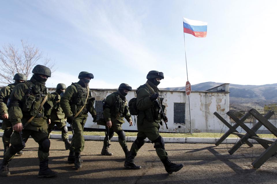 Armed men believed to be Russian servicemen march outside a Ukrainian military unit in the village of Perevalnoye outside Simferopol