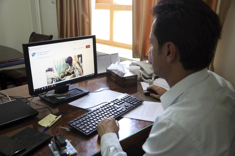 Ahmad Khalid Fahim, program director for the Swedish Committee for Afghanistan shows the group's website during an interview with The Associated Press in Kabul, Afghanistan, Wednesday, July 17, 2019. The Swedish non-governmental organization in Afghanistan said the Taliban have forced the closure of 42 health facilities run by the non-profit group in eastern Maidan Wardan province. (AP Photo/Rahmat Gul)