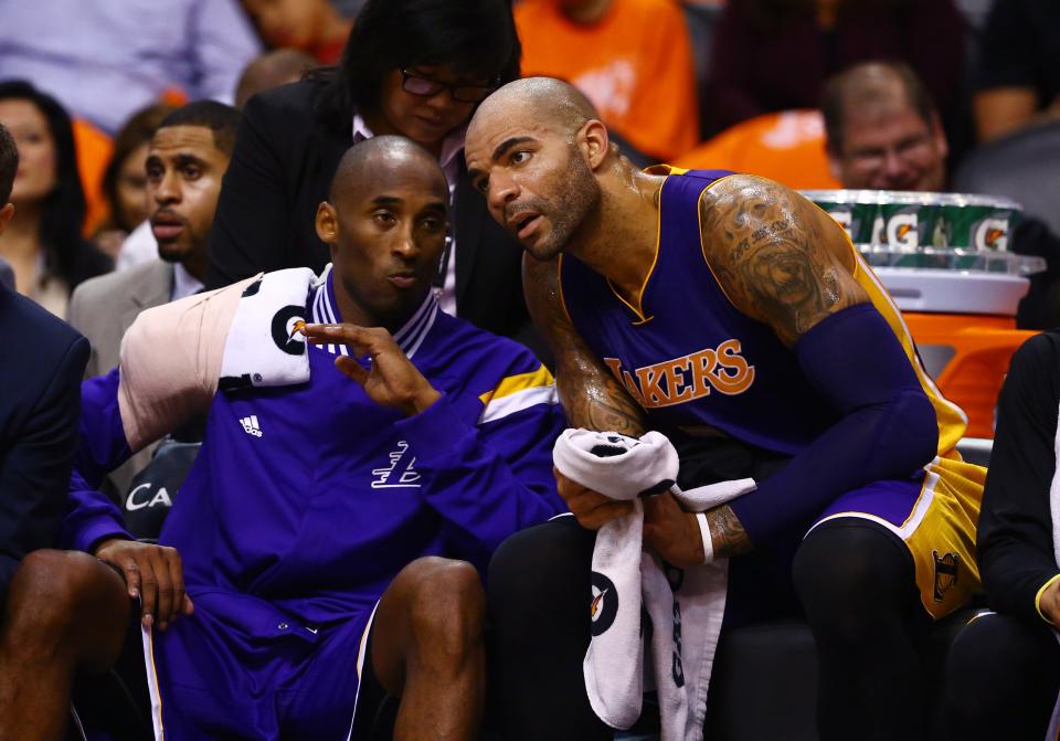 Oct 29, 2014; Phoenix, AZ, USA; Los Angeles Lakers guard Kobe Bryant (left) wears an ice pack on his right shoulder as he talks to forward Carlos Boozer on the bench in the first half against the Phoenix Suns during the home opener at US Airways Center. The Suns defeated the Lakers 119-99. Mandatory Credit: Mark J. Rebilas-USA TODAY Sports