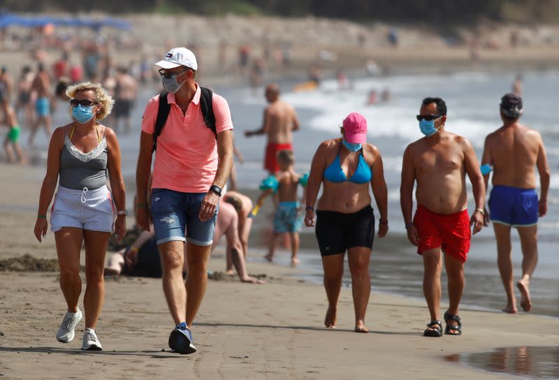 FILE PHOTO: Several people walk along the beach wearing face masks, as the regional government of the Canary Islands forbids smoking without maintaining a safe distance