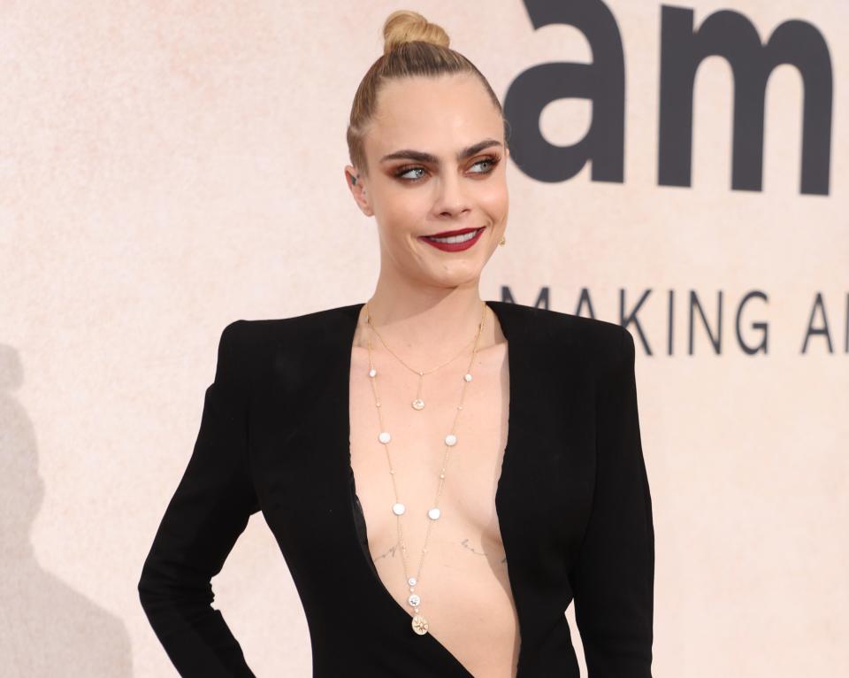 A close-up of Cara with her hair in a bun and a long-sleeved, deep-V outfit