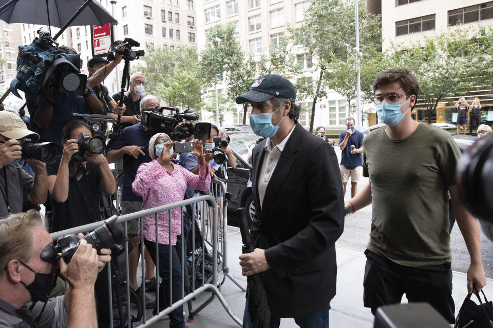 Michael Cohen, center, President Donald Trump's former personal attorney, returns to his apartment after being released from prison, Friday, July 24, 2020, in New York. District Judge Alvin Hellerstein ordered Cohen released on parole saying he believes the government retaliated against him for writing a book about Trump. (AP Photo/Mark Lennihan)