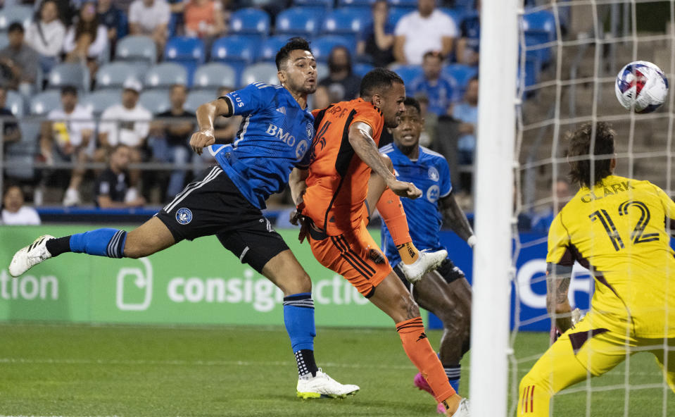 CF Montreal midfielder Mathieu Choiniere, left ,shoots wide of Houston Dynamo goalkeeper Steve Clark (12) as Dynamo midfielder Artur (6) defends during the first half of an MLS soccer match Wednesday, Oct. 4, 2023, in Montreal. (Christinne Muschi/The Canadian Press via AP)