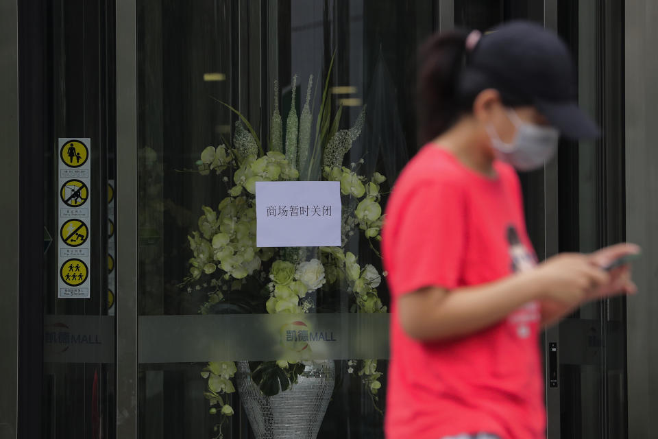 A woman wearing a protective face mask to help curb the spread of the new coronavirus walks by a shuttered shopping mall following positive cases detected in Beijing, Tuesday, June 23, 2020. China reported close to two dozen new cases of coronavirus on Tuesday a day after a city government spokesperson said containment measures had slowed the momentum of an outbreak in the capital that has infected more than 200 people. (AP Photo/Andy Wong)