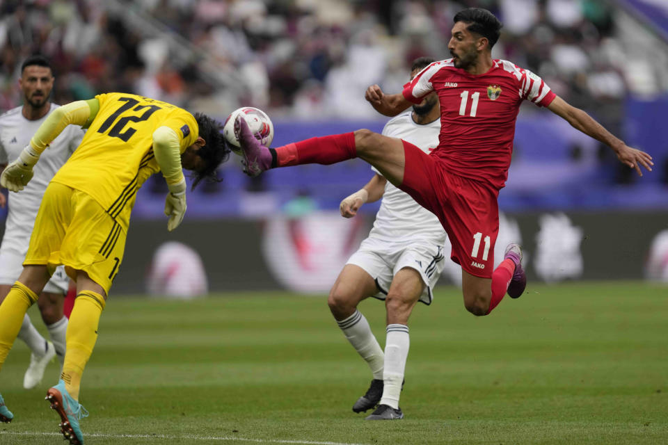 Iraq's goalkeeper Jalal Hassan makes a save with a header in front of Jordan's Yazan Alnaimat during the Asian Cup Round of 16 soccer match between Iraq and Jordan, at Khalifa International Stadium in Doha, Qatar, Monday, Jan. 29, 2024. (AP Photo/Thanassis Stavrakis)