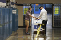 Election judge Tyler Sahnow, left, sprays hand sanitizer to John Enloe as he arrives to vote at Northeast Middle School in Minneapolis, Minnesota, during the first election in Minnesota since the full outbreak of the COVID-19 pandemic, Tuesday, Aug. 11, 2020. (Anthony Souffle/Star Tribune via AP)