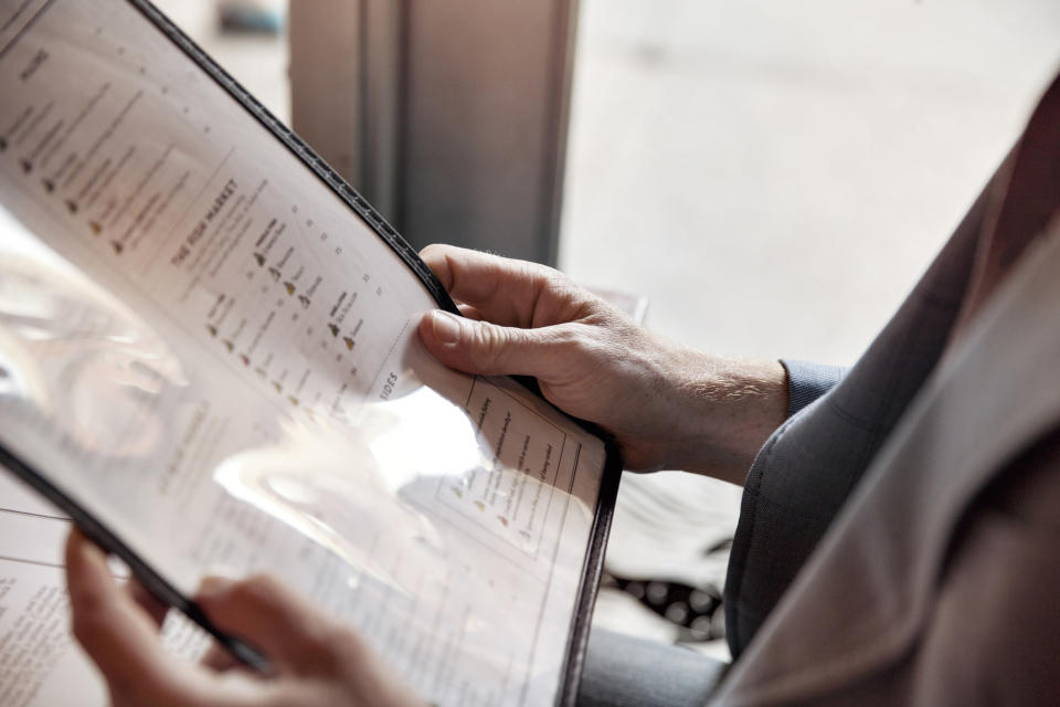 A person holding a laminated restaurant menu.