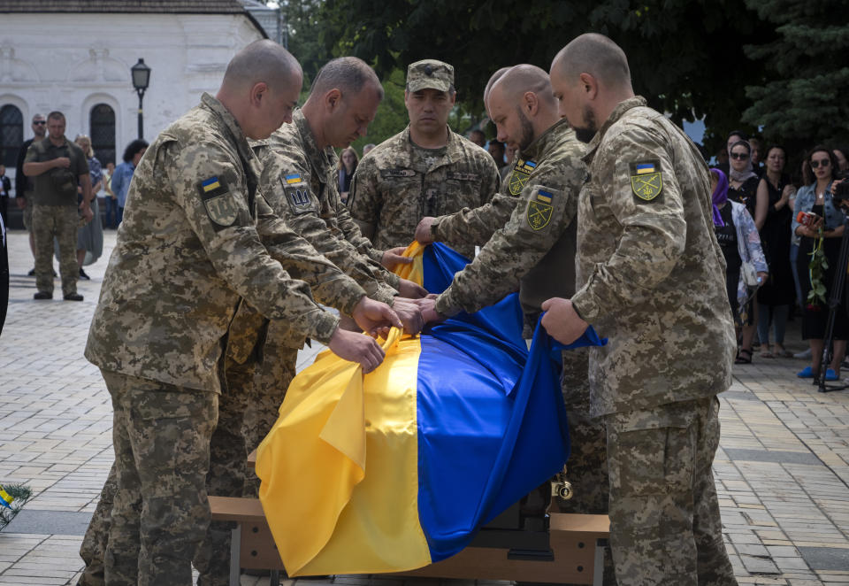 Soldiers fold a Ukrainian flag on the coffin of a soldier, codename Fanat, killed by the Russian troops in a battle, during his funeral at St Michael cathedral in Kyiv, Ukraine, Ukraine, Monday, July 18, 2022. (AP Photo/Efrem Lukatsky)