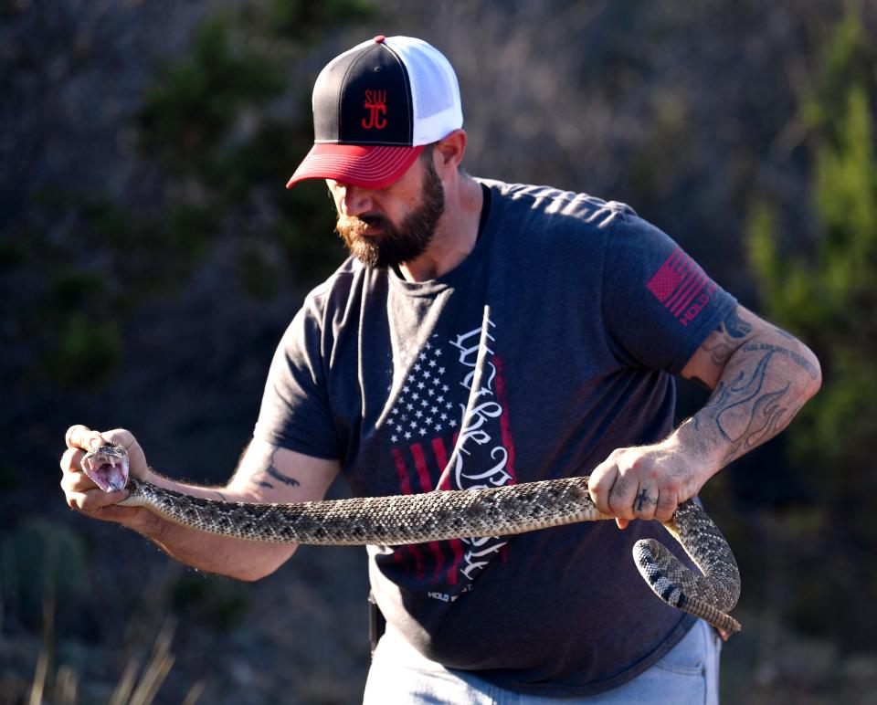 Jason Rose of the Sweetwater Jaycees holds a western diamondback rattlesnake for visitors on a bus tour.