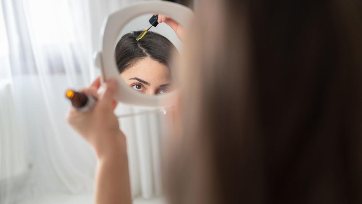 portrait of applying hair serum to her hair